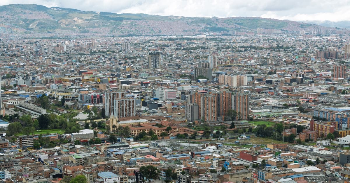 Panorámica de Bogotá con amplia zona urbana, edificaciones densas y cerros al fondo bajo cielo nublado