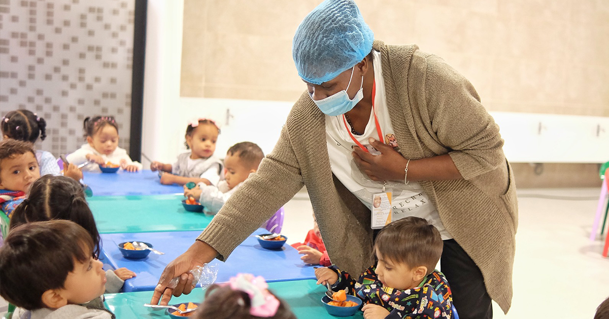 Imagen de una mujer atendiendo a niños y niñas en un comedor