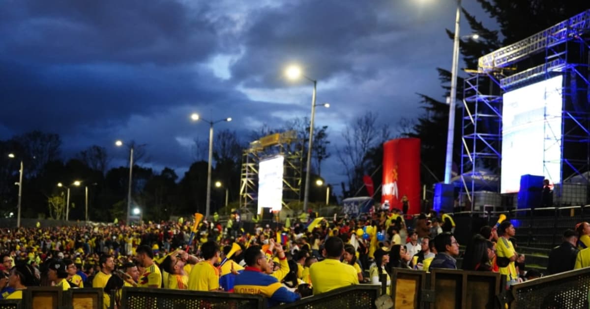 Personas reunidas en parque de Bogotá durante transmisión pública de partido de la Selección Colombia en pantallas gigantes