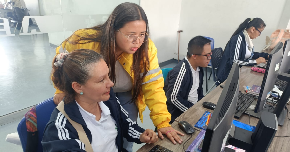 Imagen de una funcionaria ayudándole a una señora en un computador