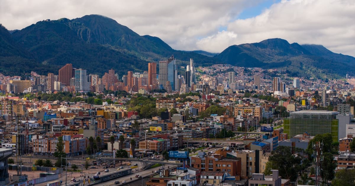Vista panorámica de Bogotá con edificios residenciales, zona financiera y cerros orientales bajo cielo parcialmente nublado