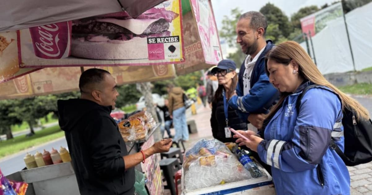 Foto de un vendedor informal junto a gestores sociales del IPES en una calle de Bogotá.
