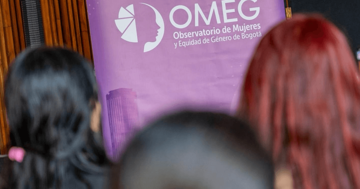 Mujeres con una pancarta del OMEG de fondo.
