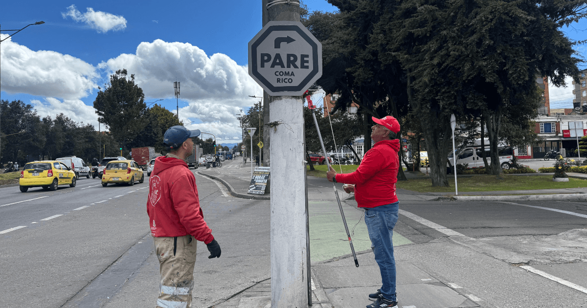 Defensores del espacio público retirando un pendón ilegal del mobiliario público.