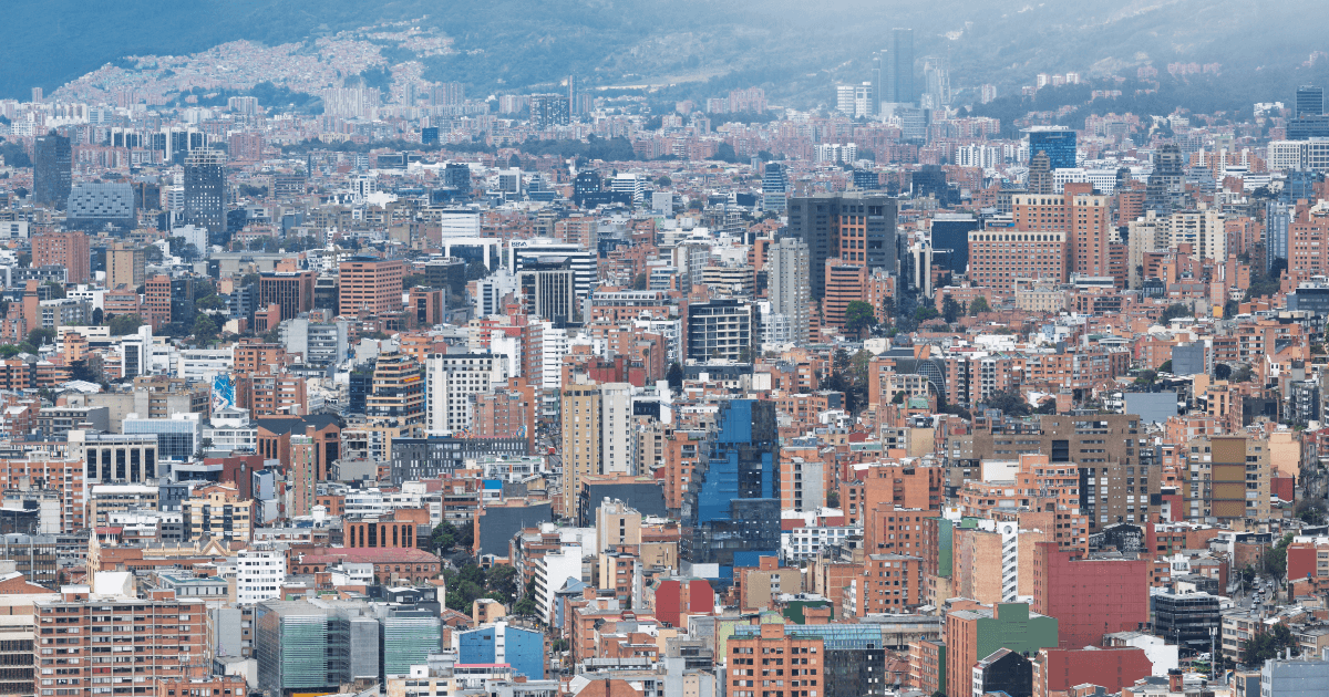 Vista panorámica de Bogotá con edificios residenciales y comerciales, centro financiero, cerros orientales y cielo parcialmente nublado.