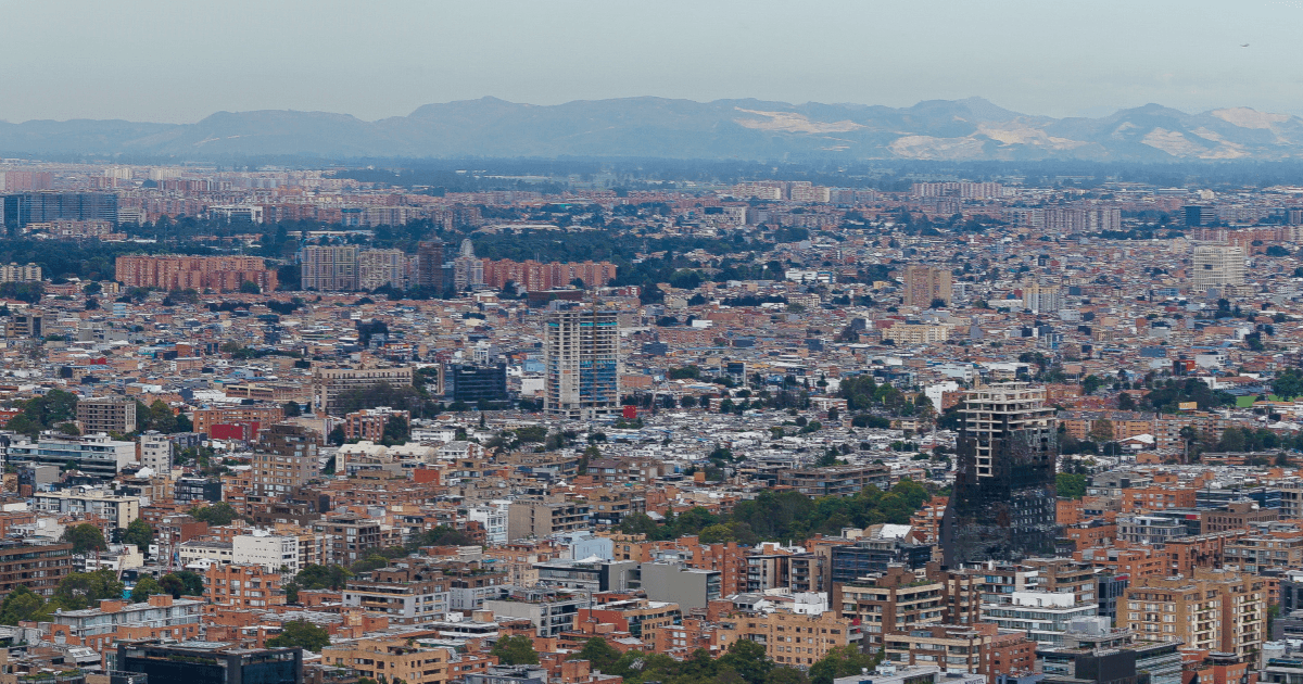 Vista panorámica de Bogotá con edificaciones residenciales y comerciales, cerros orientales al fondo y paisaje urbano.