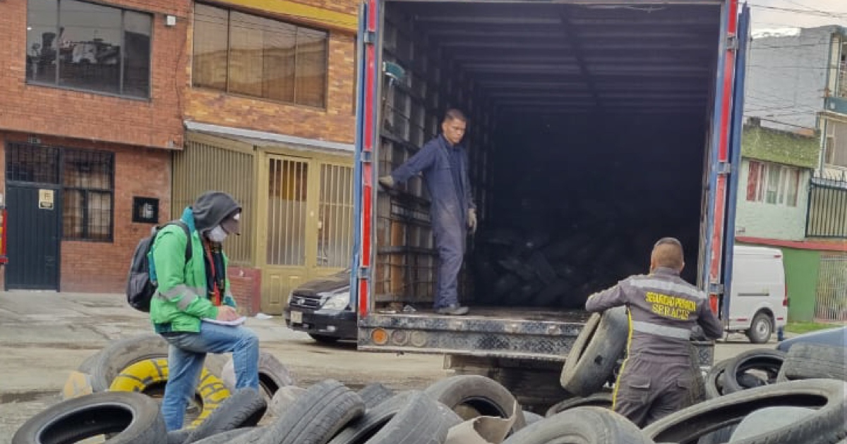 Foto que muestra personas recolectando llantas y colocandolas en un camión 