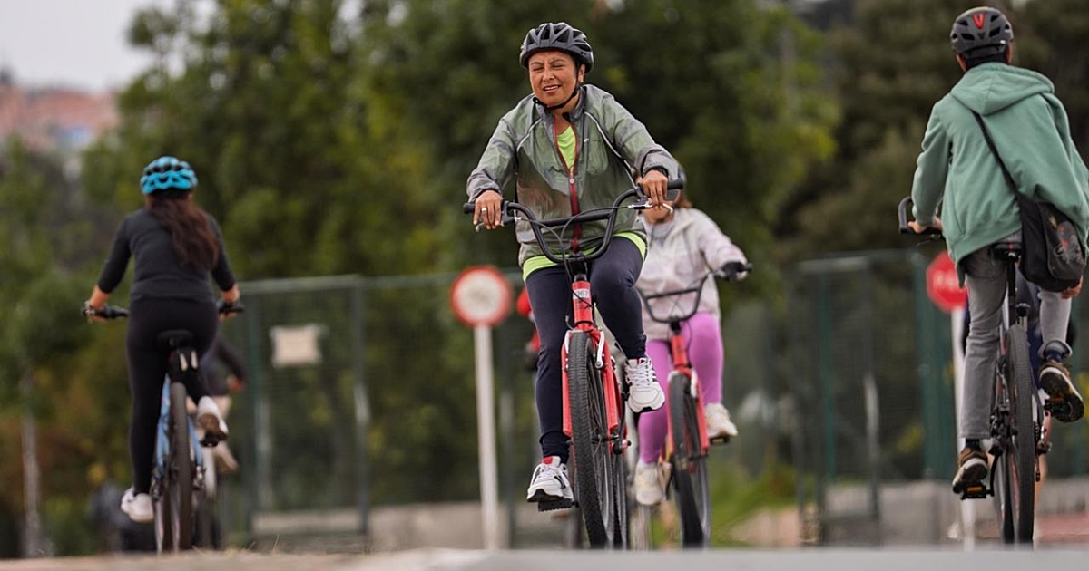 Personas recorren una ciclorruta en bicicleta durante una jornada recreativa rodeada de zonas verdes en Bogotá.