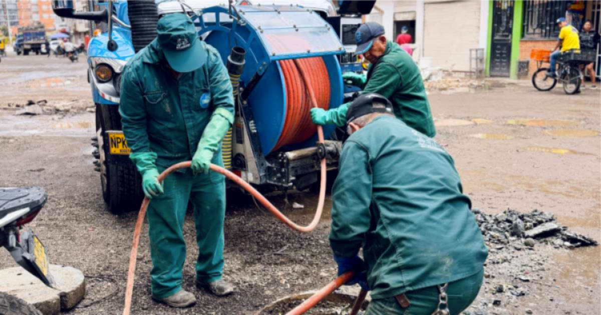 Imagen de tres técnicos de la empresa de Acueducto realizando mantenimiento en un tubo de alcantarillado, de fondo se ve un carro tanque.