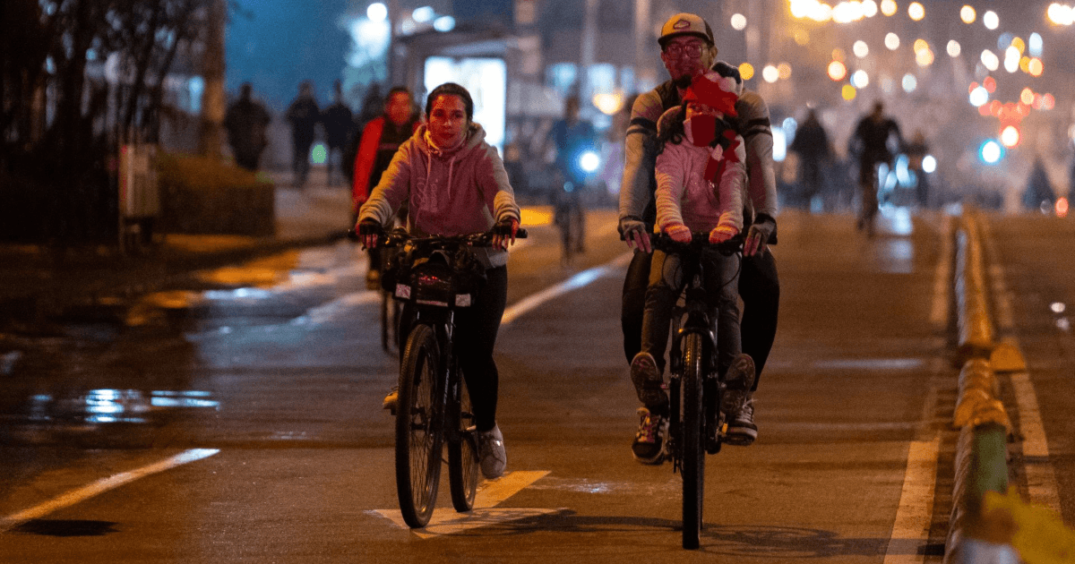 Personas recorren en bicicleta una vía iluminada de Bogotá durante una jornada de Ciclovía nocturna