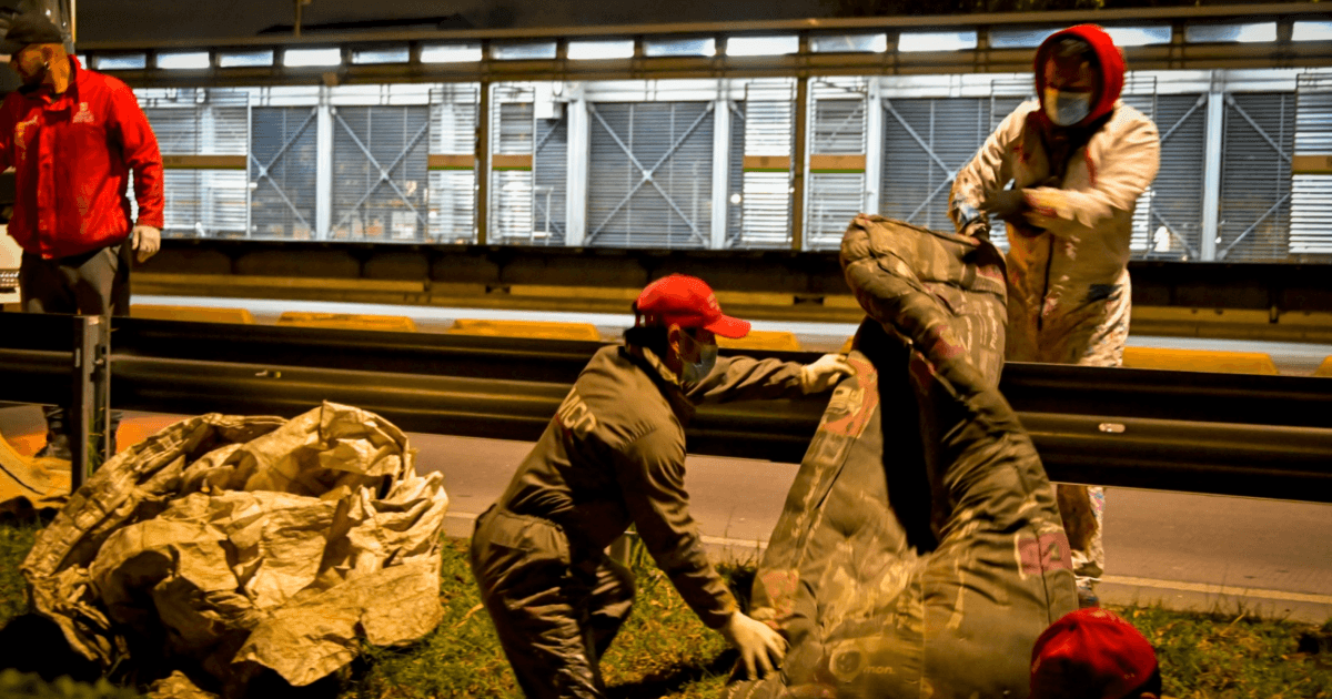 Trabajadores del Distrito levantando cambuches del separador de una vía de Bogotá.