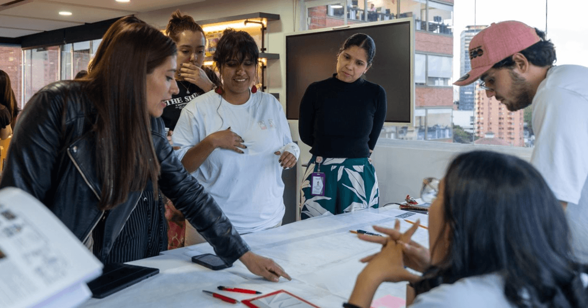 Mujeres y hombres reunidas trabajando en una mesa.