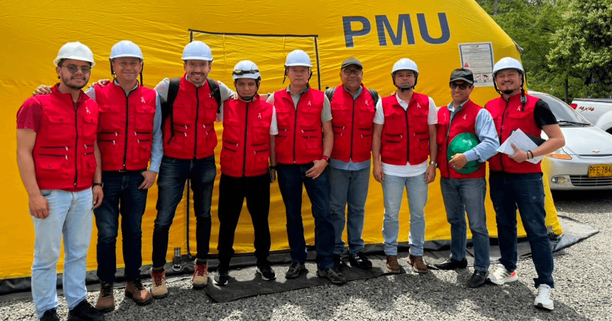Foto que muestra un grupo de personas con chaleco rojo y casco blanco sonriendo 