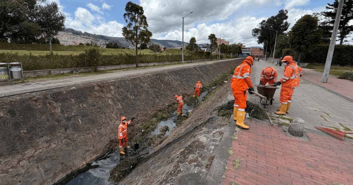 Foto que muestra personas con el uniforme de Aguas Bogotá limpiando un canal de agua