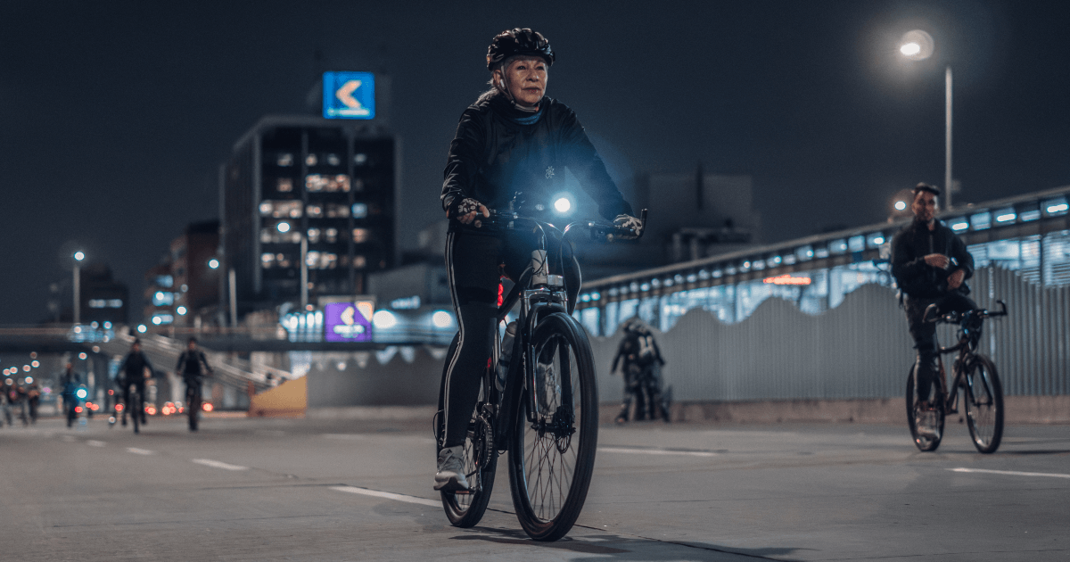 Mujer transita en bicicleta en calle de Bogotá durante Ciclovía Nocturna.