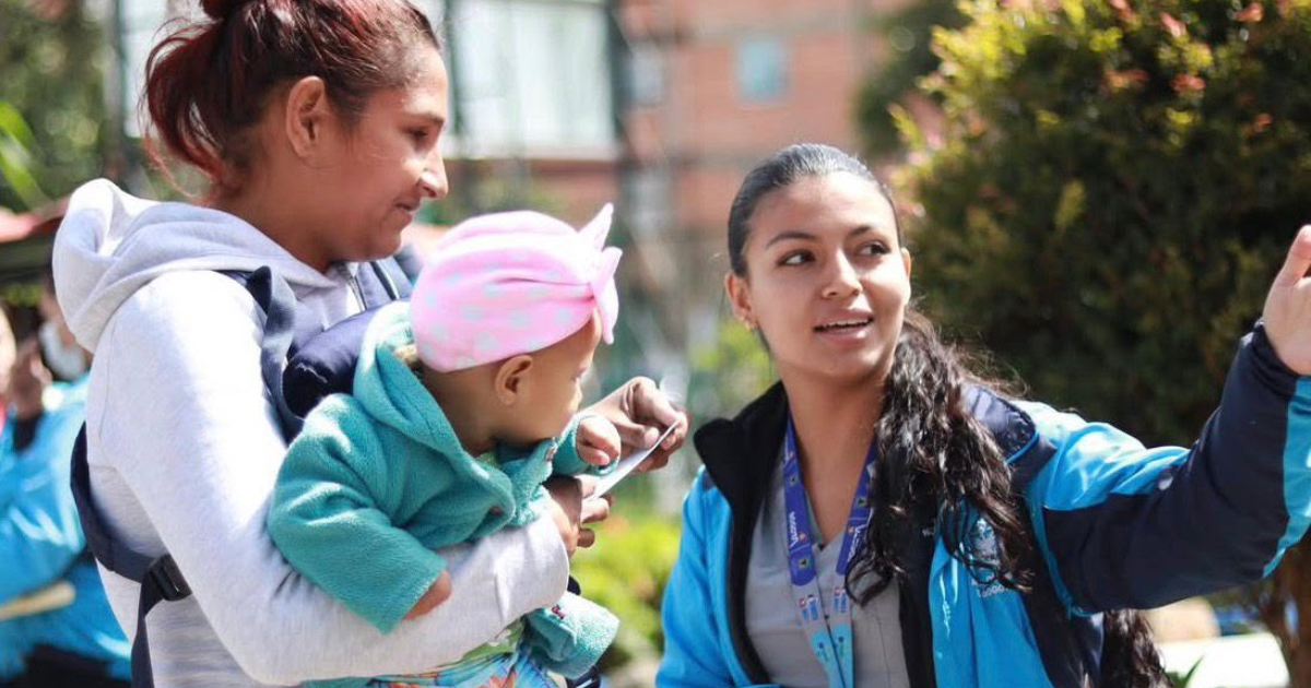 Foto de una funcionaria orientando a una madre con su bebe