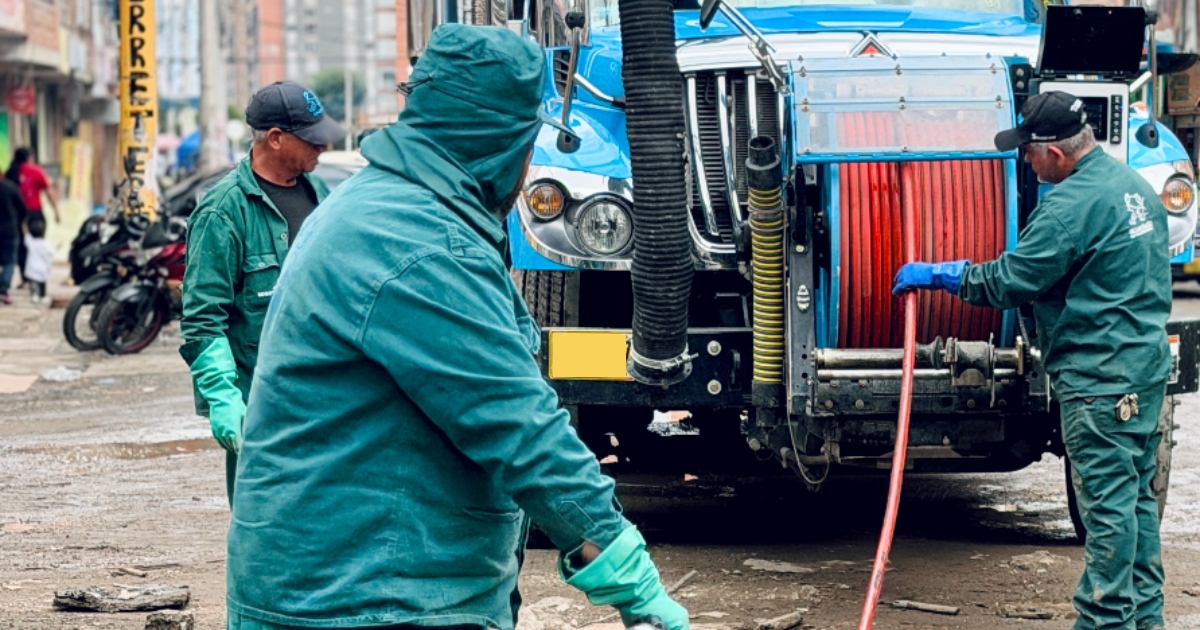 Foto que muestra personas con el uniforme del Acueducto de Bogotá limpiando el suelo