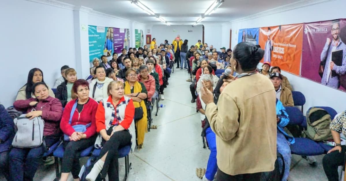 Adultos mayores y jóvenes reunidos en un salón conversando 