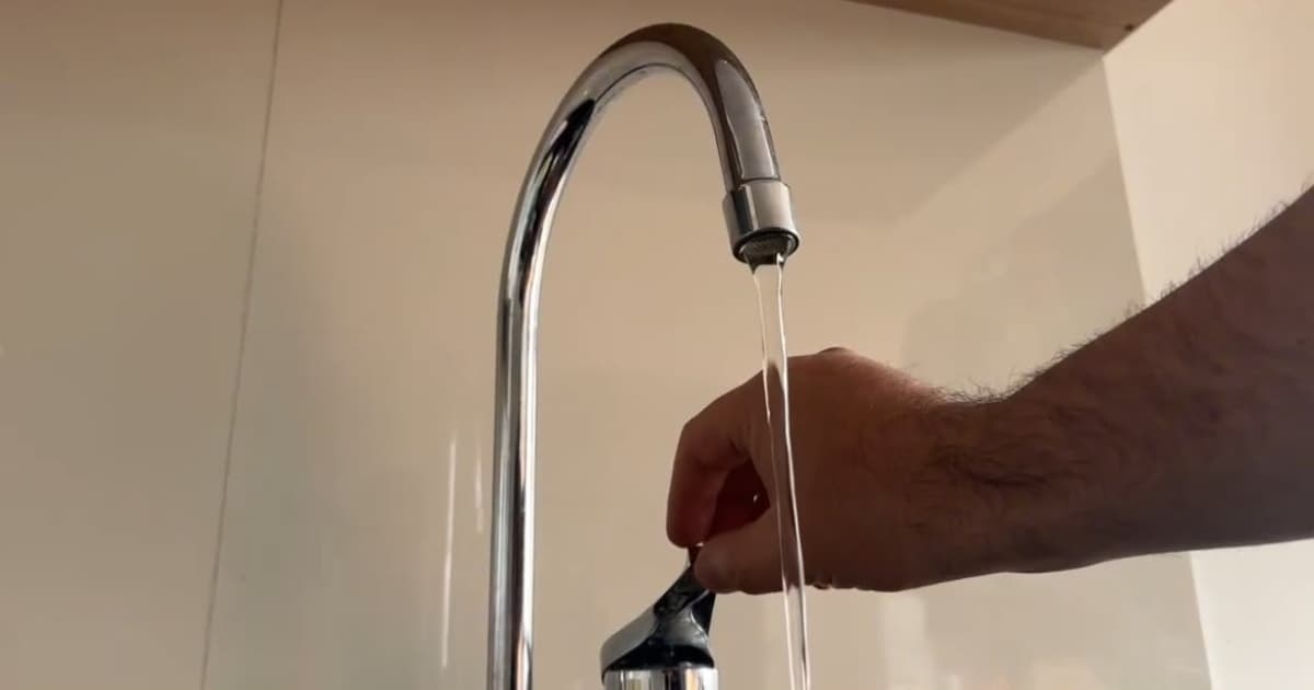 Una persona abriendo una llave de agua en una vivienda en Bogotá.