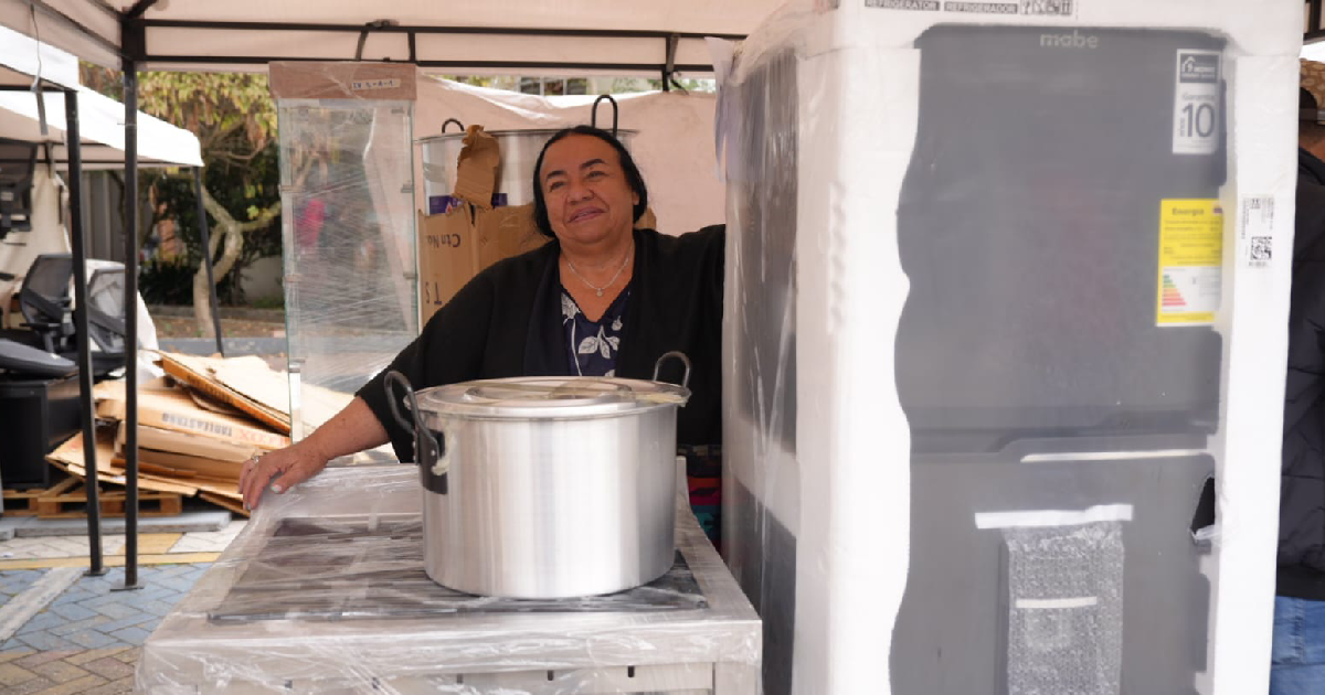 Mujer con una nevera y una olla, para apoyo a su emprendimiento en Bogotá.