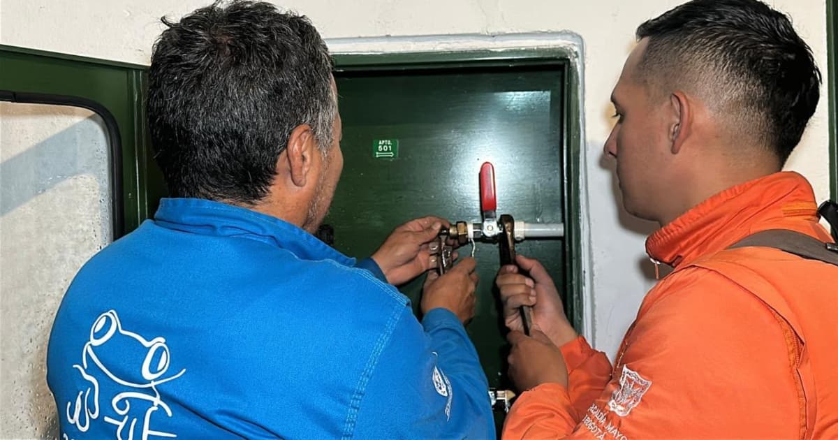 Dos funcionarios del Acueducto revisando el medidor del agua