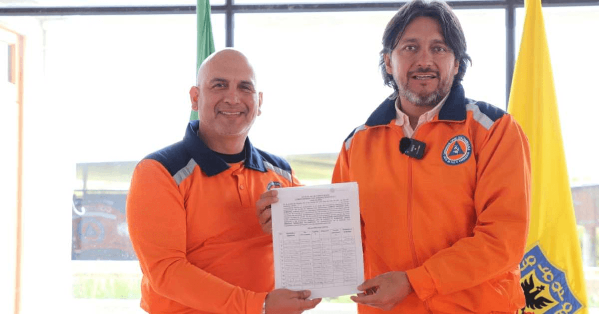 Foto que muestra dos personas sonriendo con un documento en la mano