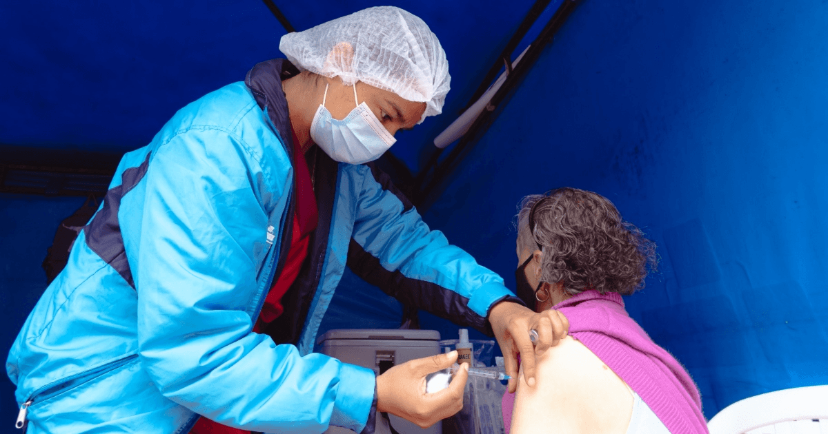 Foto que muestra un enfermero colocando una vacuna en un brazo de una mujer