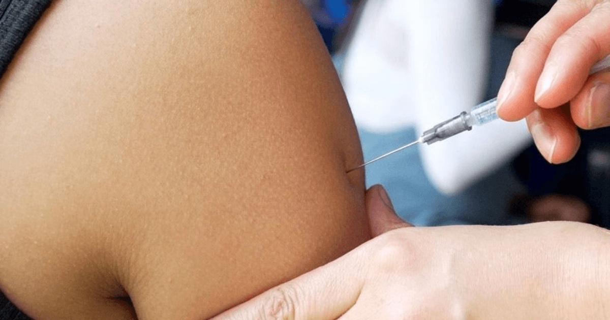 Foto que muestran unas manos colocando una vacuna en un brazo 