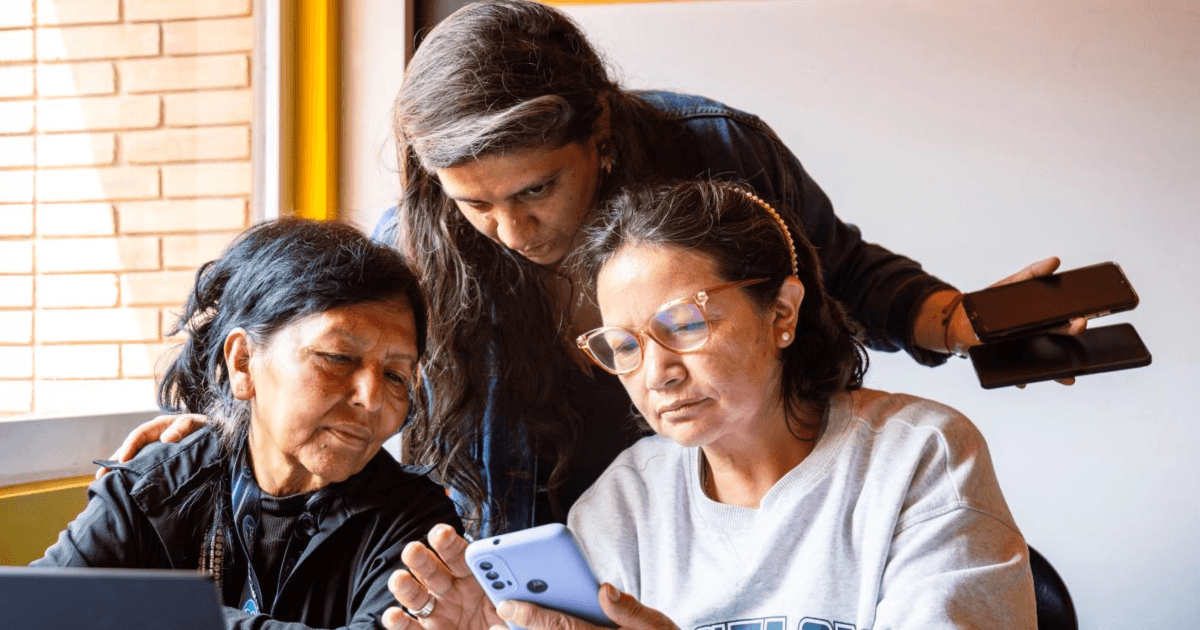 Tres mujeres viendo un celular durante un encuentro en Bogotá.