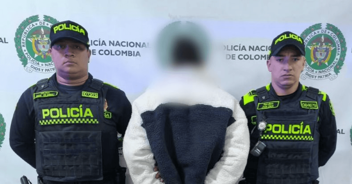Hombre capturado, de espaldas, en medio de dos policías.