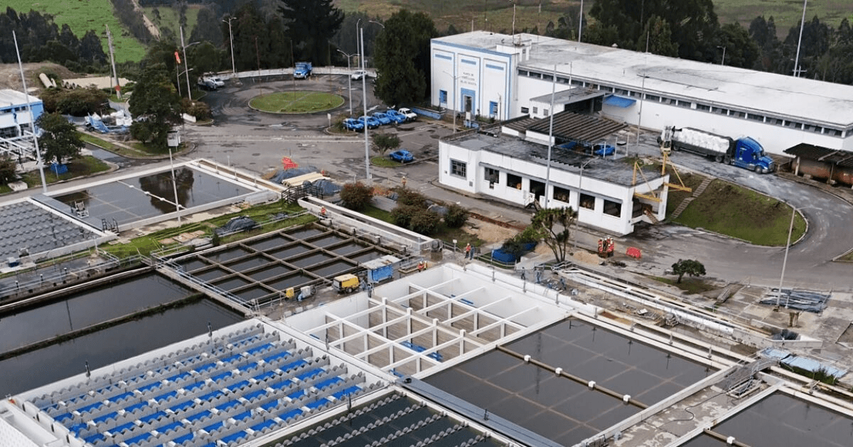 Foto que muestra una planta de tratamiento de aguas y edificios blancos en el fondo