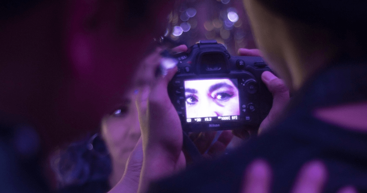 Imagen de una cámara fotográfica en cuyo lente se ven los ojos de una mujer
