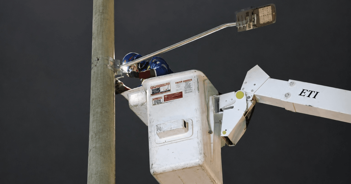 Foto que muestra una persona realizando labores de mantenimiento en un poste de luz 
