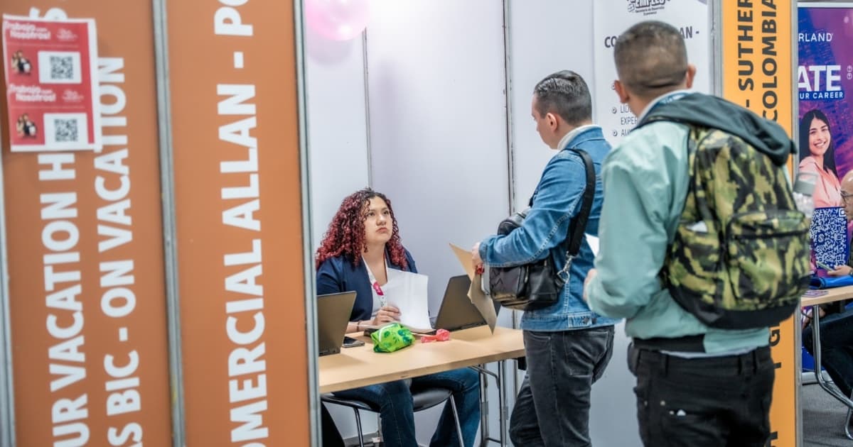 Dos hombres en una feria de empleo junto a una funcionaria de la Secretaría Distrital de Desarrollo Económico
