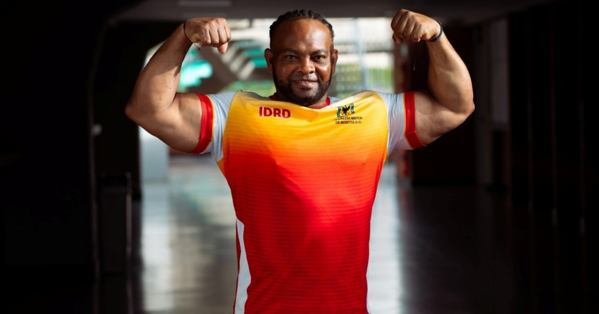 Foto de deportista de parapowerlifting mostrando su entrenamiento físico portando la camiseta del Equipo Bogotá color naranja.