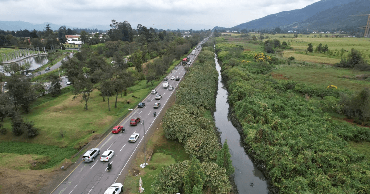 Vista aérea de la Autopista Norte de Bogotá con tránsito vehicular junto a un canal de agua y amplias zonas verdes que serán atendidas por el PMU.