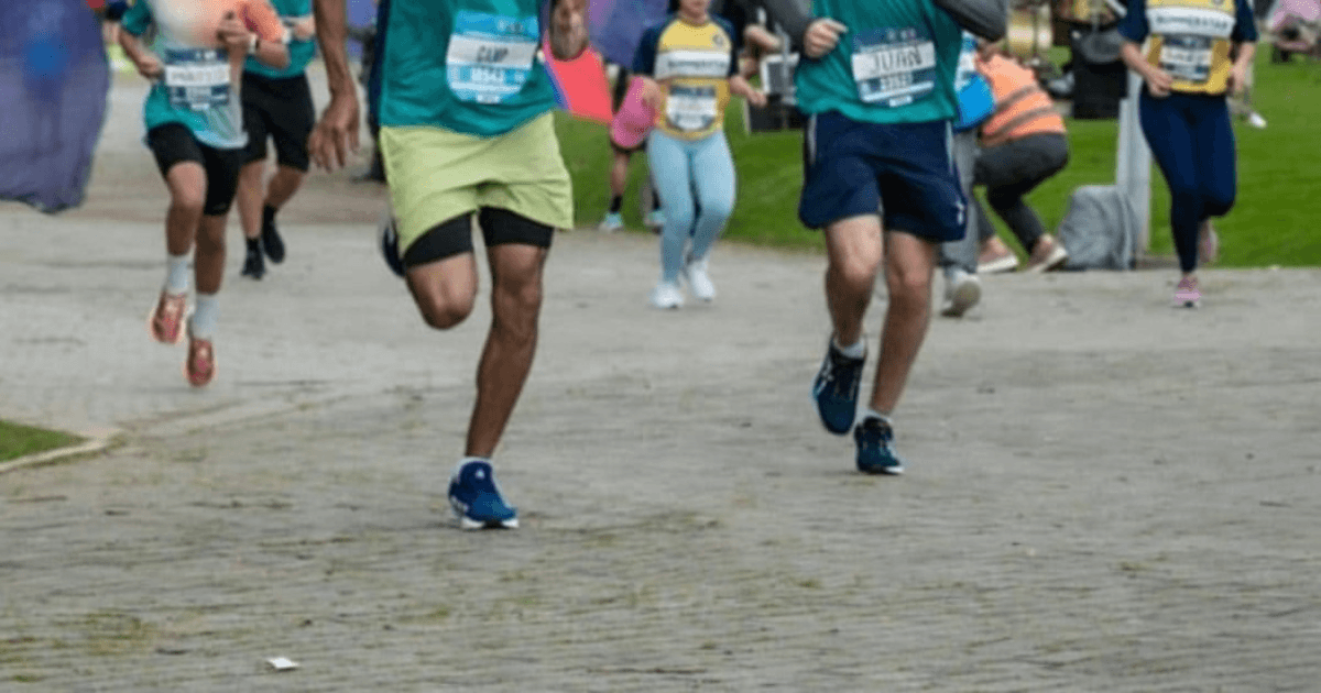 Primer plano de las piernas de varios corredores mientras participan en una carrera atlética sobre una vía pavimentada.