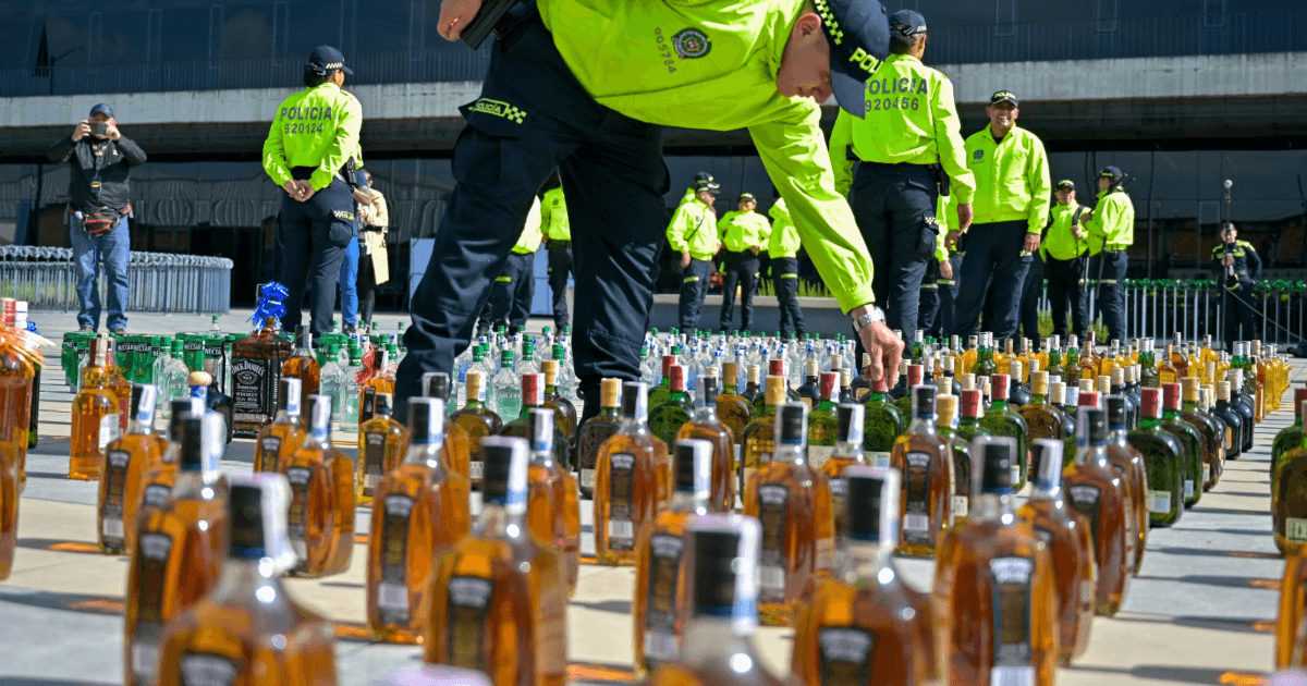 Foto de policías exponiendo en el piso botellas incautadas.