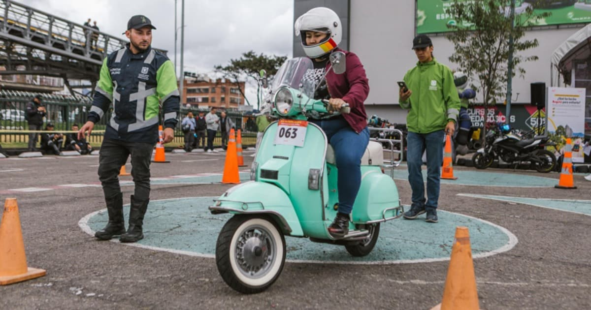 Foto de una mujer en una moto junto a personal de Secretaría de Movilidad en el marco de una actividad