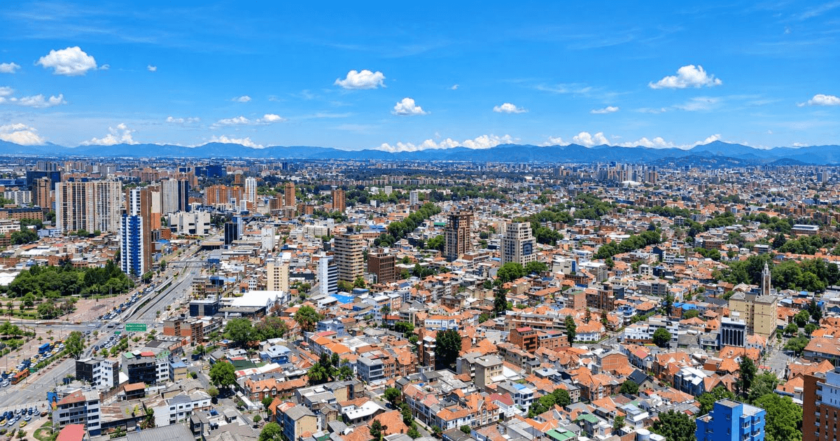 Vista panorámica de Bogotá desde gran altura, con una amplia zona urbana compuesta por viviendas de teja roja, edificios residenciales y vías vehiculares.