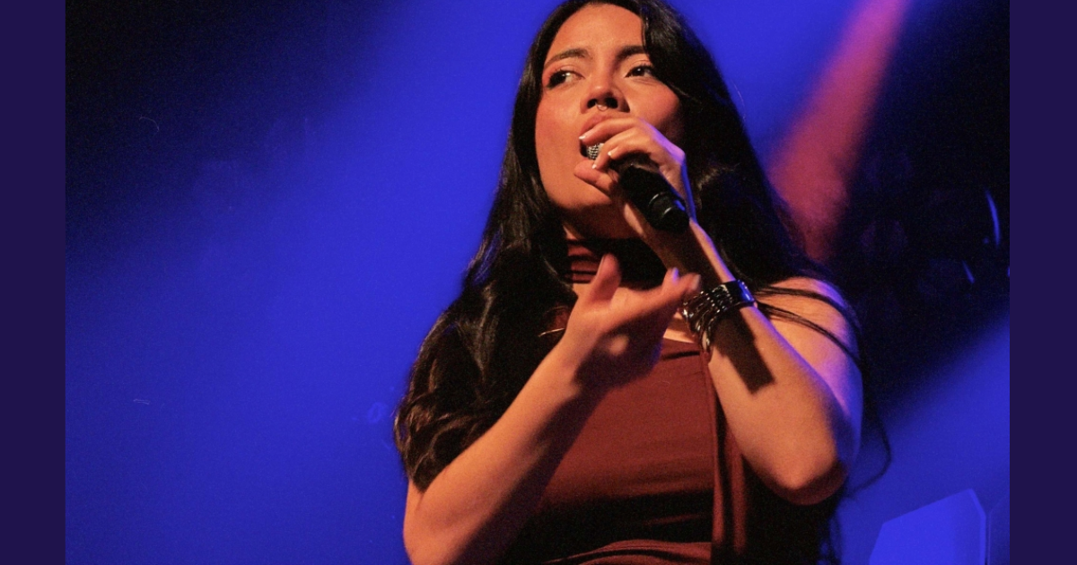 Imagen de una mujer joven que canta con un micrófono en su mano.