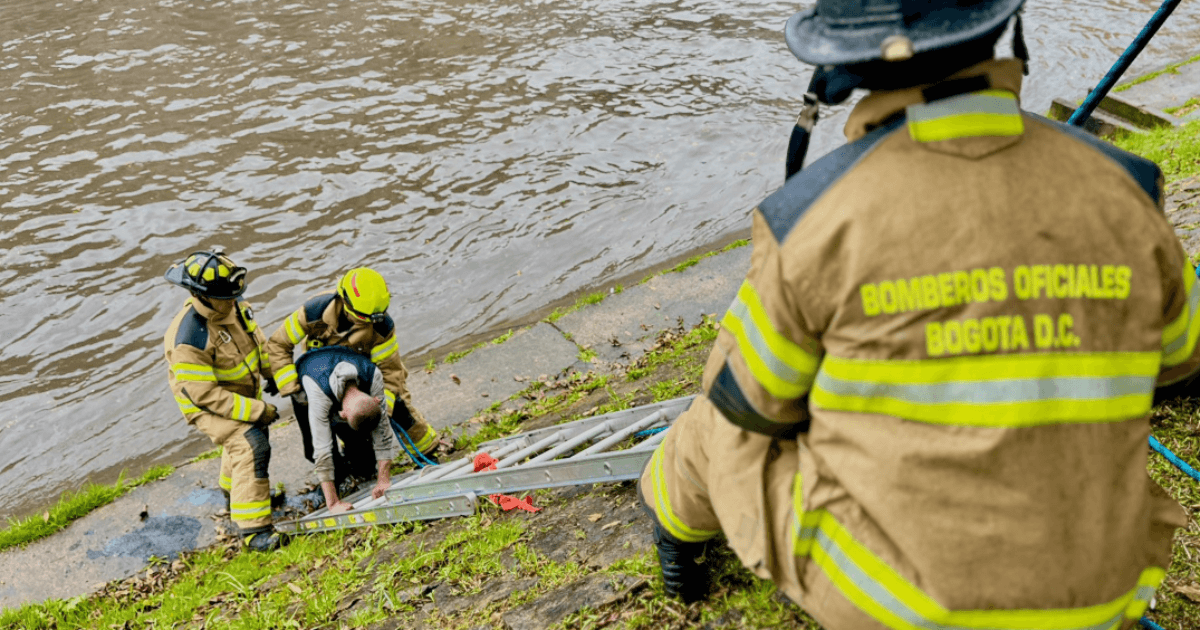 Bomberos rescatando a dos hombres que cayeron al canal de la avenida NQS.