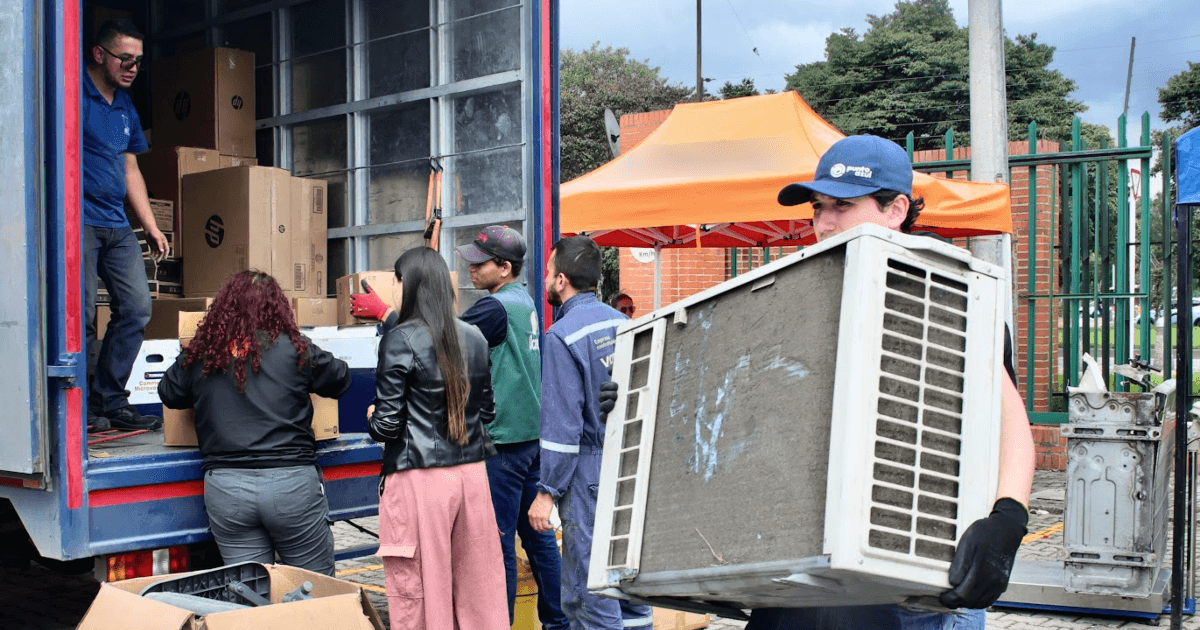 Personas entregan y descargan equipos electrónicos y cajas de cartón durante Reciclatón 2026 de residuos posconsumo, frente a un camión de carga habilitado para recibir los materiales.
