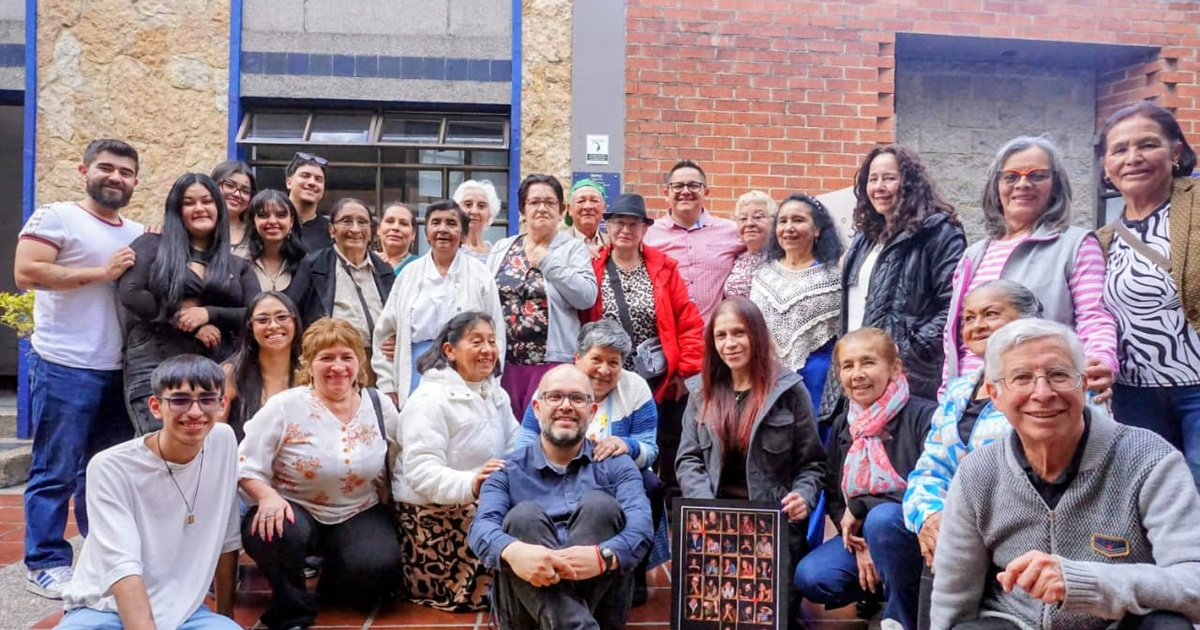 Foto de un grupo de personas de diferentes edades posando para una fotografía frente a un edificio.