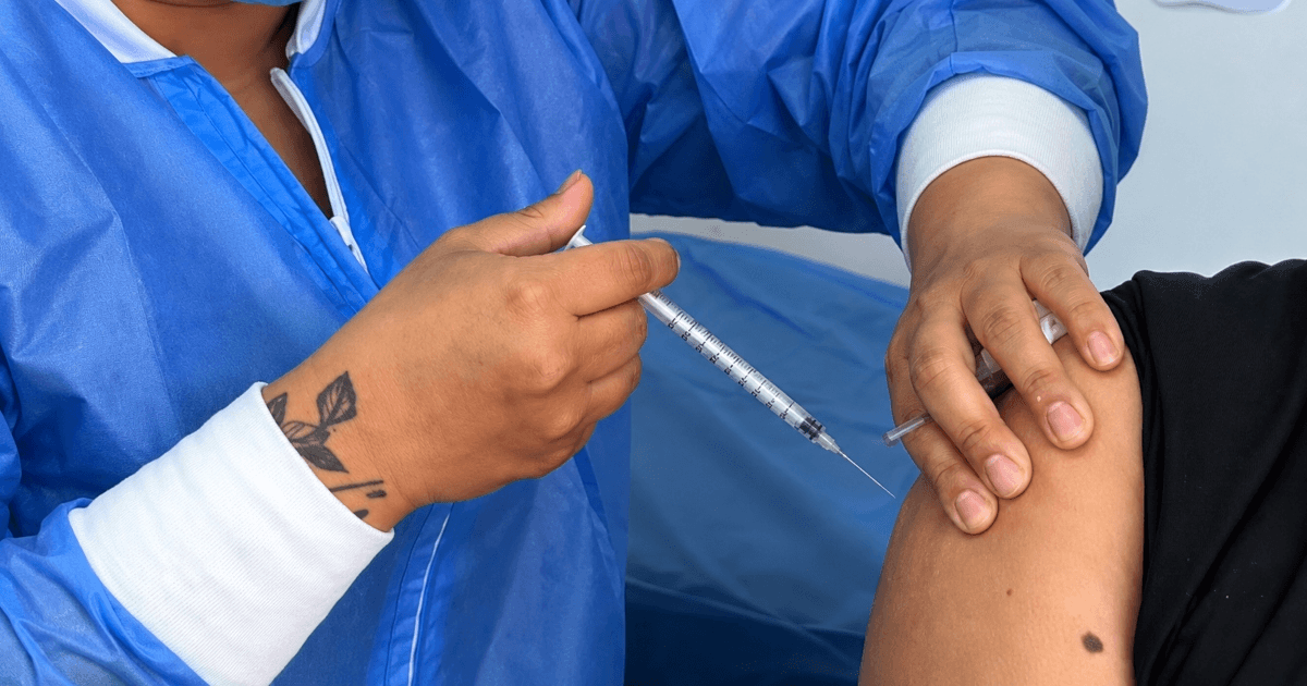 Foto que muestran unas manos colocando una vacuna en un brazo