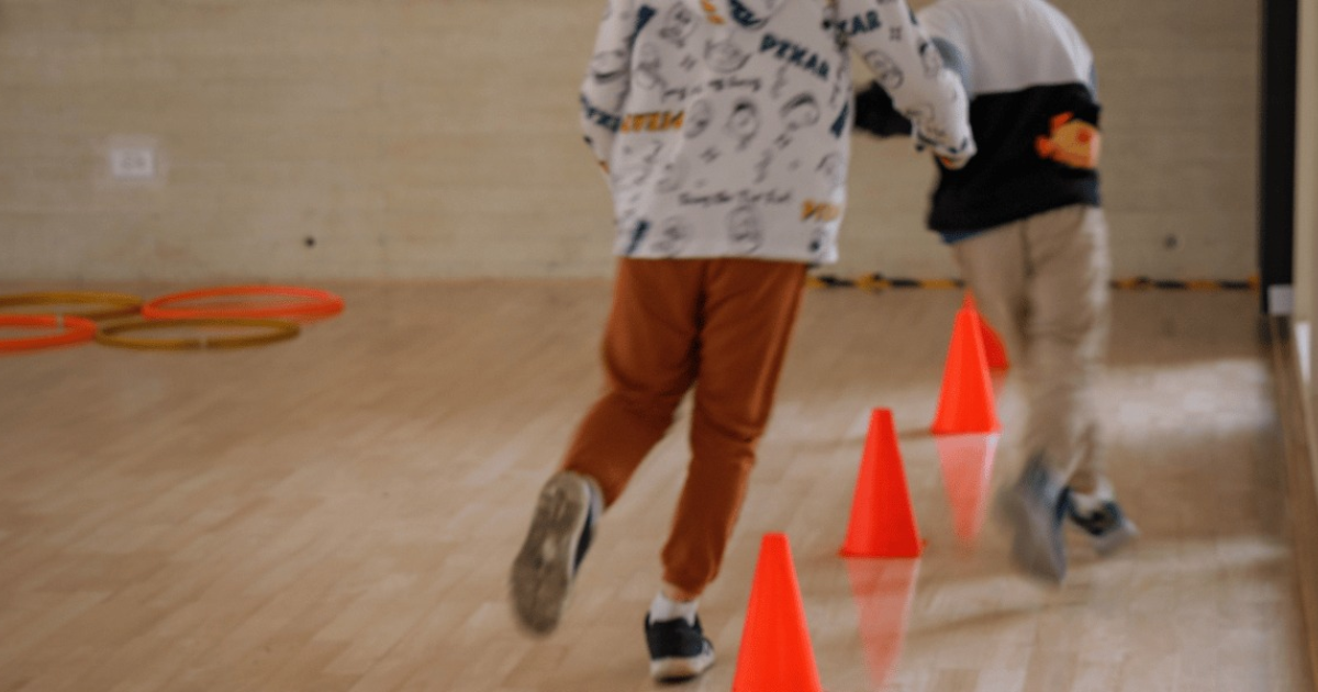 Imagen de dos niños juagando con conos plasticos de color naranja ubicados en el piso