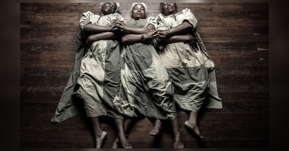 Imagen de tres mujeres afrocolombianas acostadas y cogidas de las manos entrecurzadas