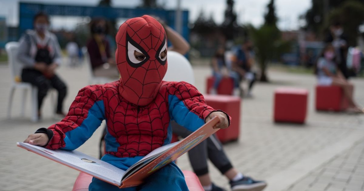 Fotografía niño disfrazado de spiderman con un libro abierto