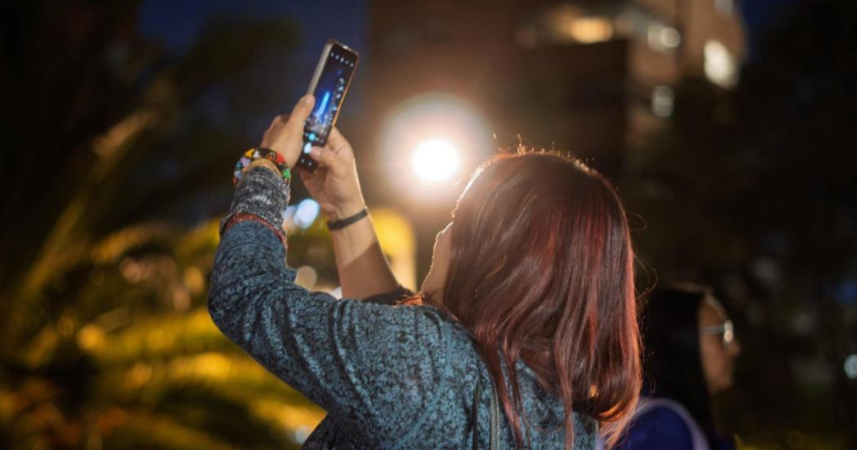 Imagen de mujer tomando foto en caminata nocturna