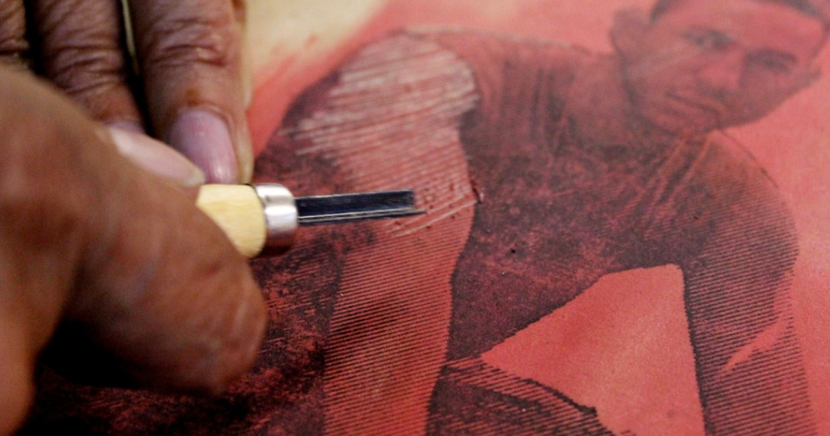 Imagen de una mano trabajando el grabado de una imagen de un hombre en una pieza textil 